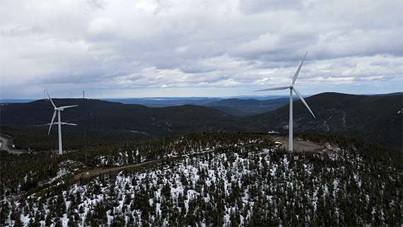 Deux éoliennes sur le Mont Miller, en Gaspésie. Il y a encore un peu de neige au sol parmi les arbres.