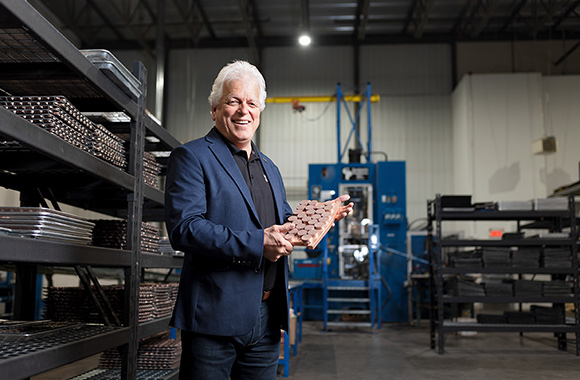 Christian Babin, fondateur de de Kuma Brakes, est debout au centre de l’entrepôt de et tient une plaquette de freins d’éolienne dans ses mains.