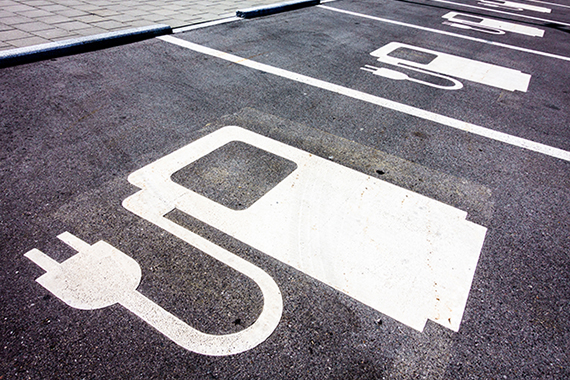 Espaces de stationnements asphaltés pour les voitures électriques, identifiés par un pictogramme peint sur le sol et représentant une borne de recharge électrique.