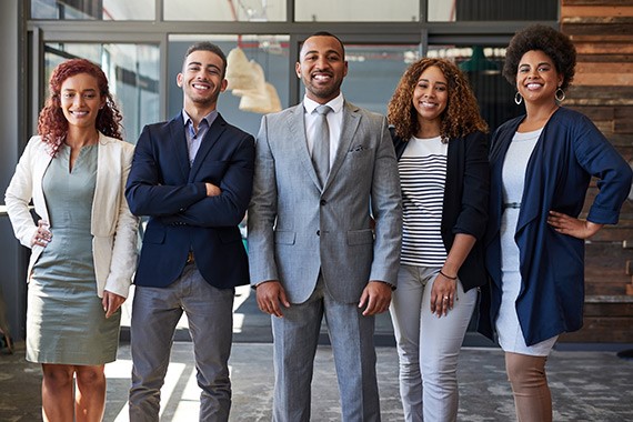 Jeunes gens d’affaires issus des communautés noires posant ensemble, tout sourire.