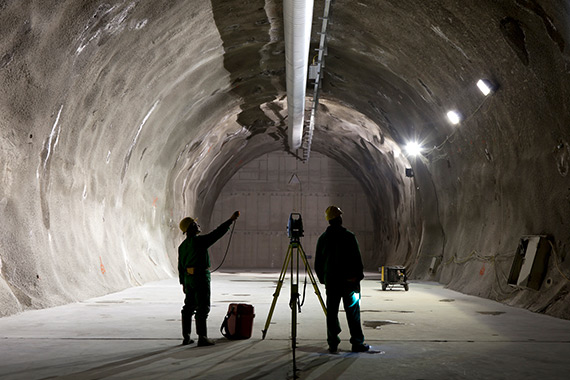Deux employés étudient la paroi d’un tunnel minier.