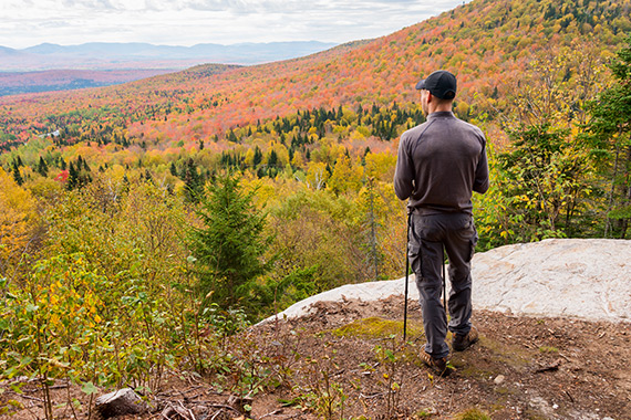 Marcheur admirant un paysage d’automne dans un sentier de montagne.