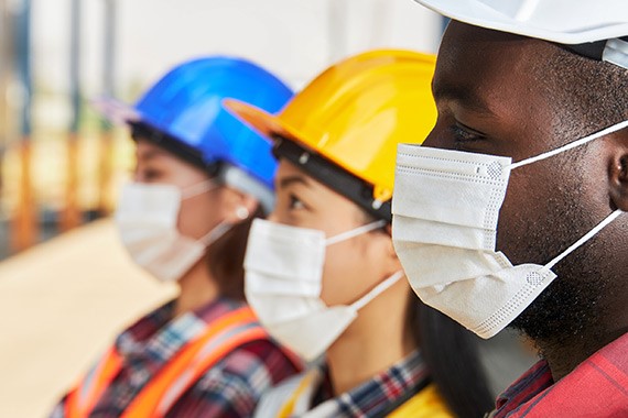 Photo du visage de trois ouvriers du bâtiment portant des masques comme mesure sanitaire en prévention de la COVID-19.